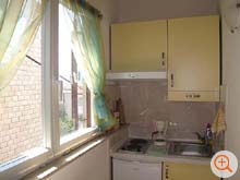 the kitchenette of Riba with stove, exhaust hood, coffee machine and fridge with freezer